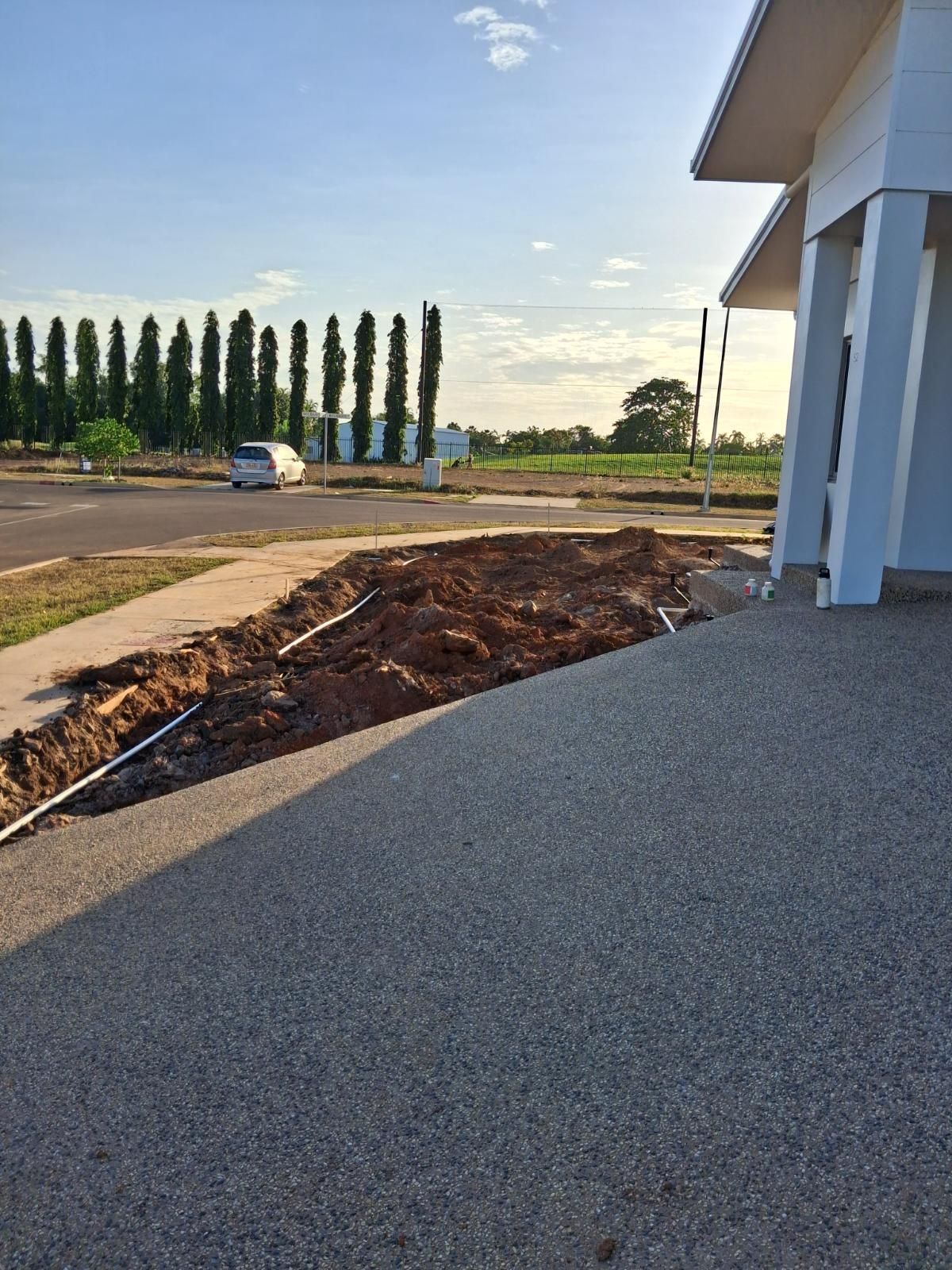 Stone driveway and freshly dug garden bed next to a modern house under a clear sky in Marrara Gardens Northern Territory
