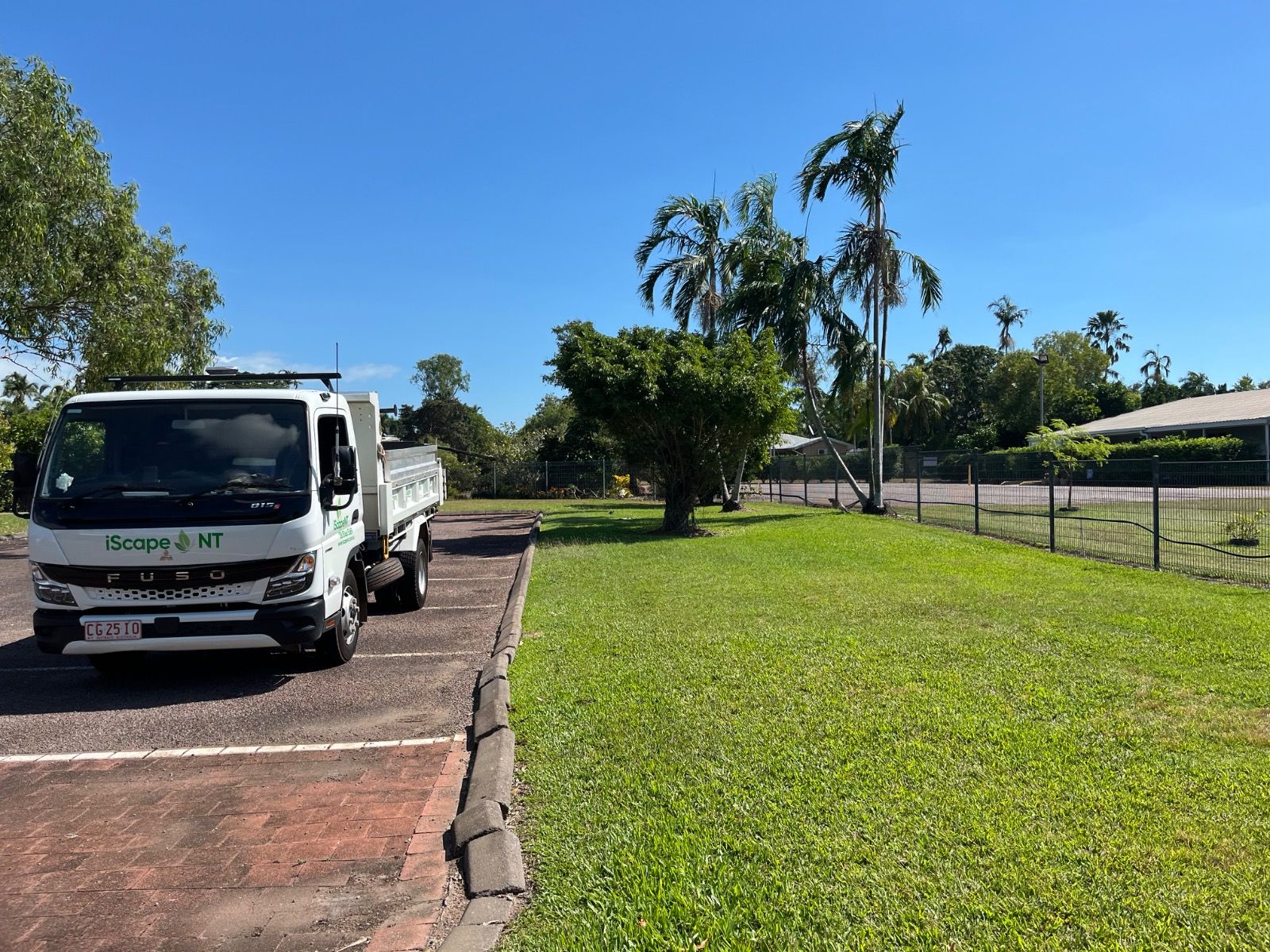iScape NT truck parked on a paved area next to a green lawn with trees and a fence under a clear blue sky in Leanyer Northern Territory